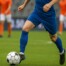 Image of a footballer wearing a blue kit dribbling a ball