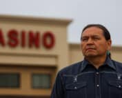 Indigenous leader standing in front of casino building representing Ontario First Nation legal dispute over casino revenue agreements