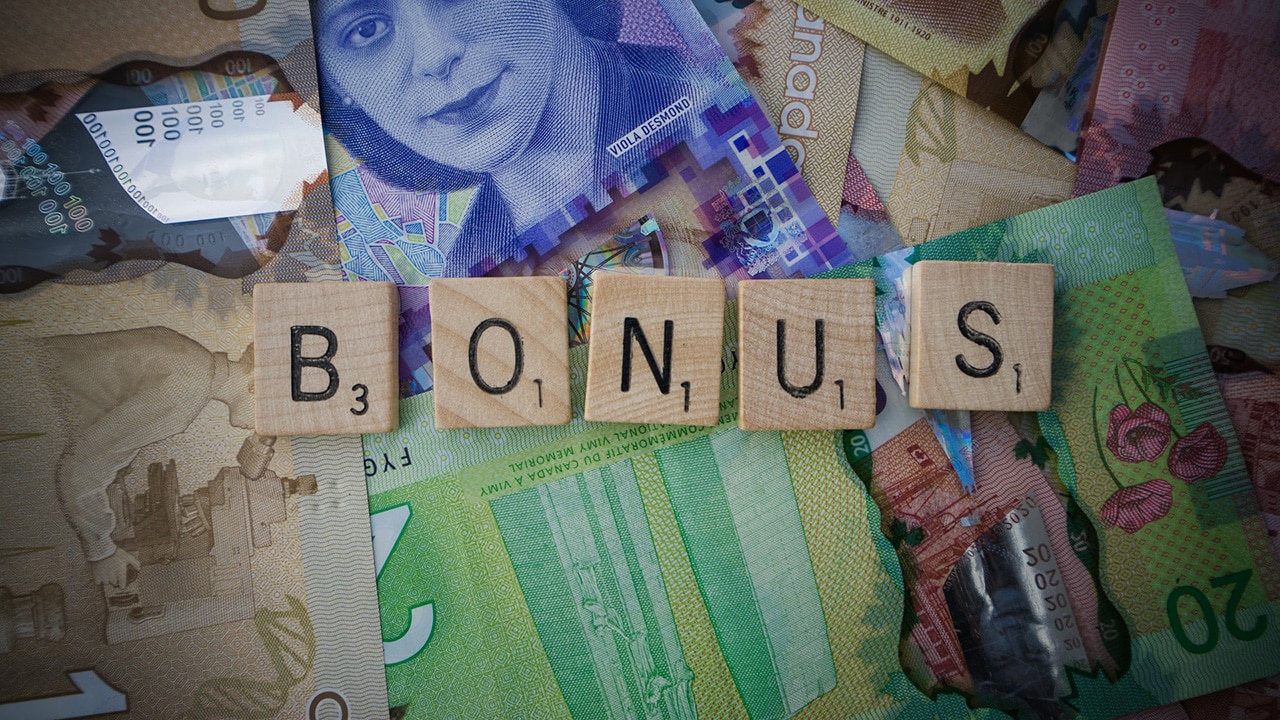 Mehre Geldscheine liegen durcheinander darauf liegen Buchstabensteine als Wort Bonus